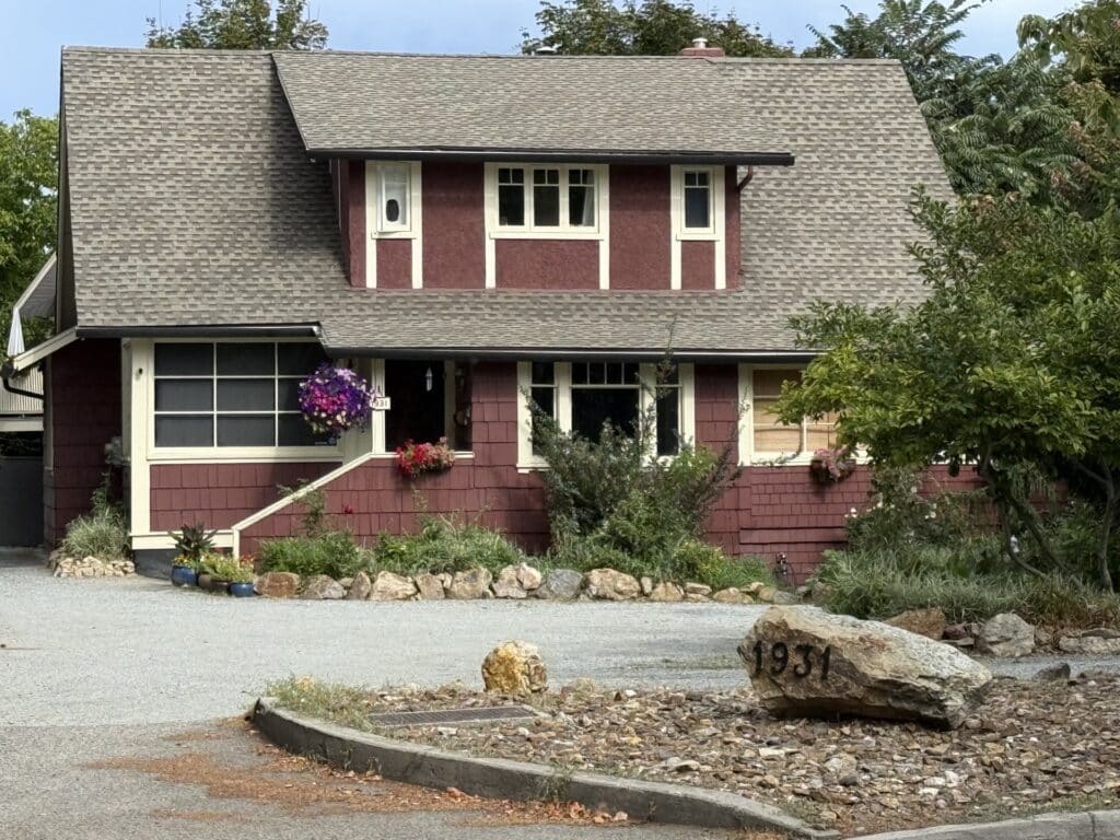T. Treadgold House at 1931 Abbott Street in Kelowna, with red shingle siding, white trim and a broad sloping roof.
